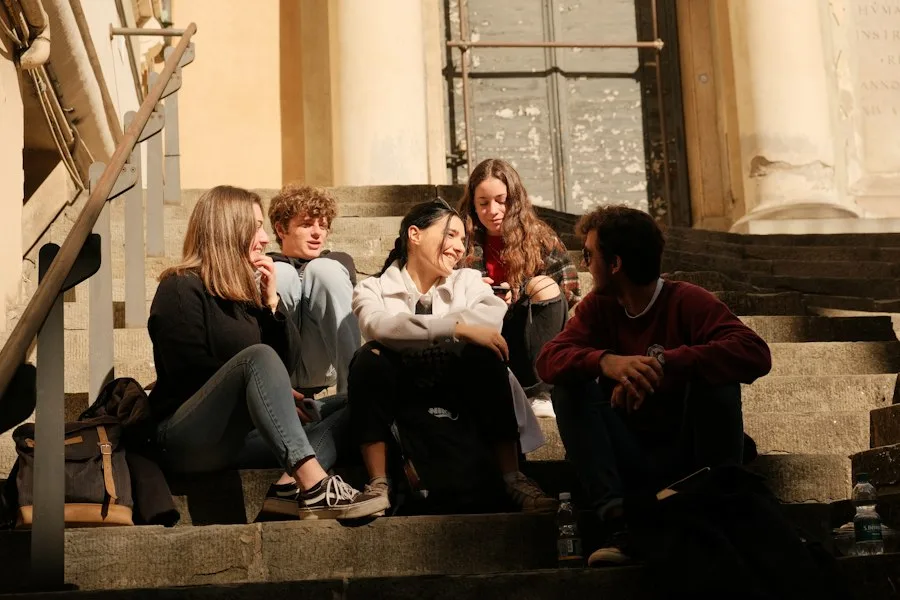 Young people sitting together on sunny steps, talking and laughing
