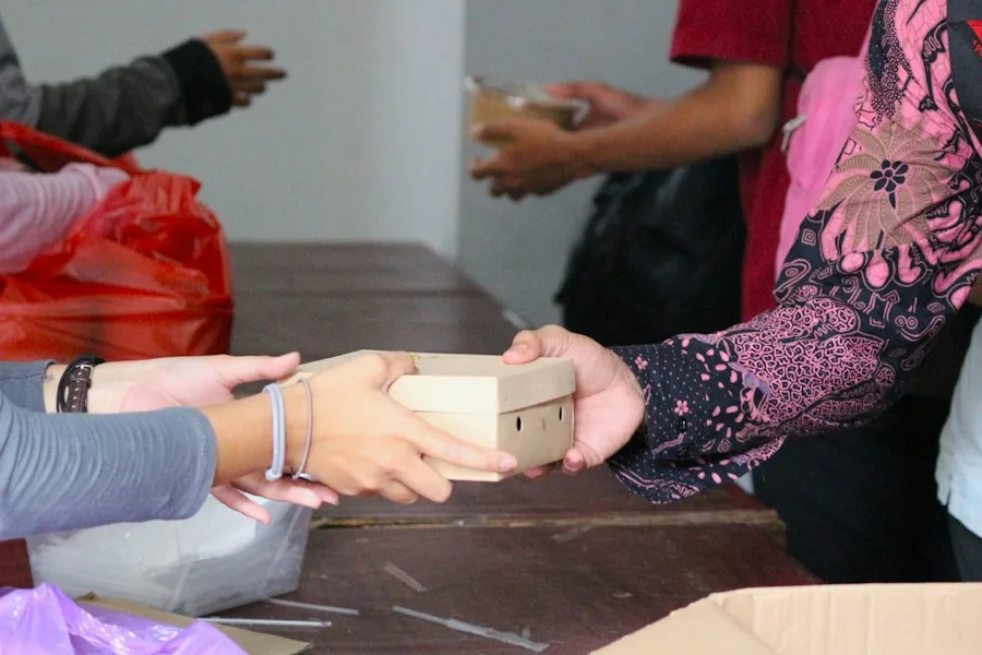 Volunteer handing a box of donated goods across a distribution table